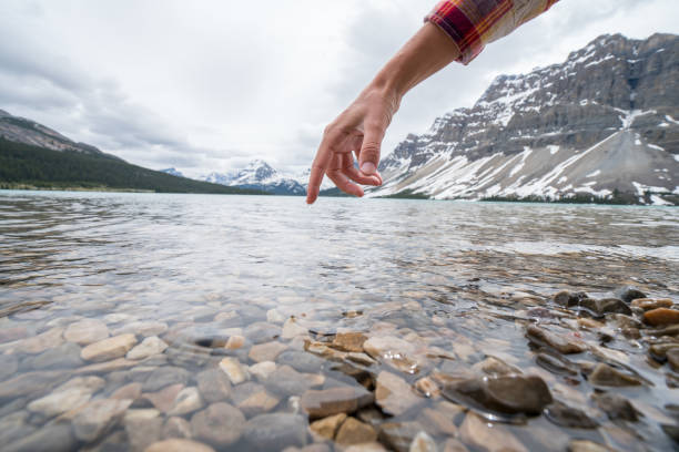 istock Finger touches surface of mountain lake 858948882