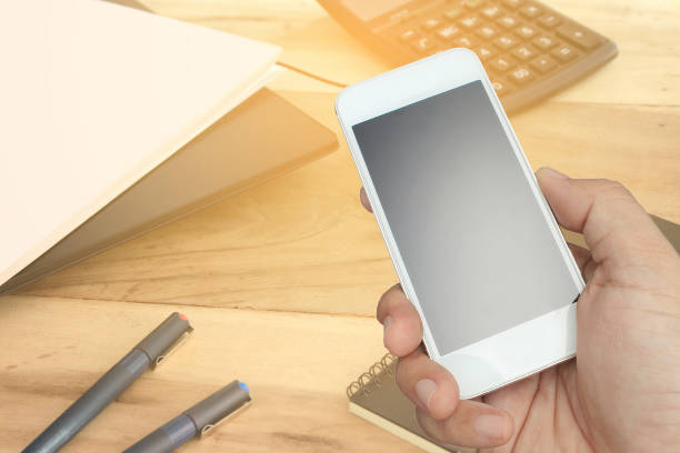 istock hand hold and touch screen smart phone and office desk 858954854