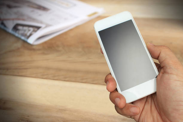 istock hand hold and touch screen smart phone and newspaper 858954866