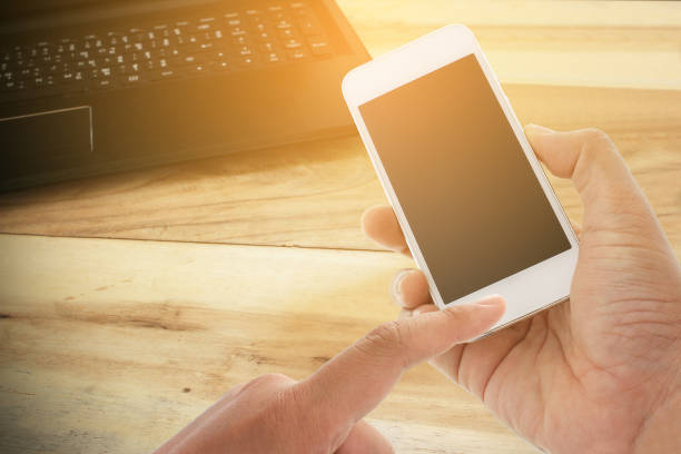 istock hand hold and touch screen smart phone and office desk 858954876