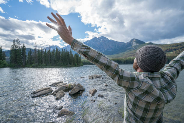 istock Young man arms outstretched by the lake 858954978
