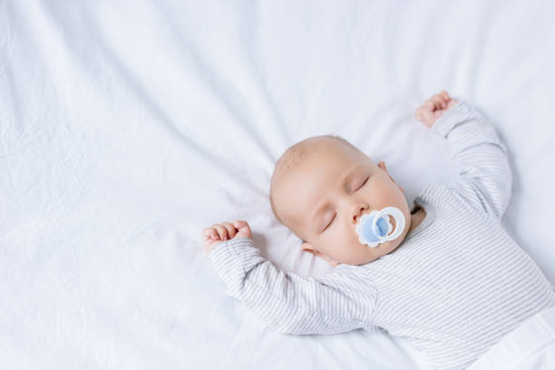 bebé con chupete en la boca para dormir en cama - sleeping baby fotografías e imágenes de stock