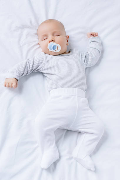 istock baby with pacifier in mouth sleeping on bed 858967784