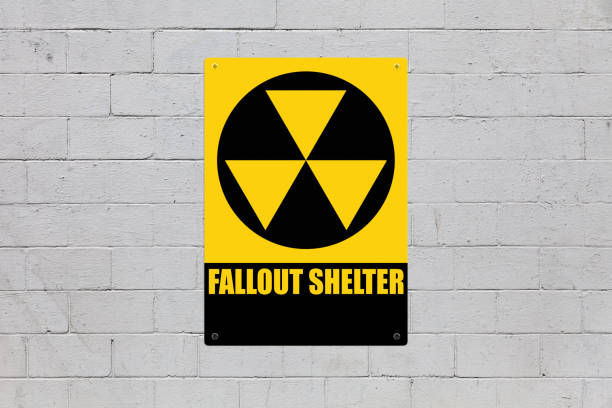 Fallout shelter sign Yellow warning sign screwed to a brick wall to warn about a threat. In the middle of the panel, there is a nuclear symbol and the message is saying "Fallout shelter". nuclear fallout stock pictures, royalty-free photos & images