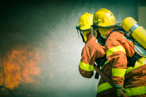 2 firefighters spraying water in cinematic tone stock photo