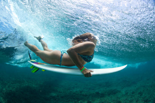 istock Brunette surfer girl duck dives 858977998
