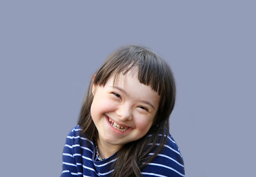 Cute smiling down syndrome girl on the blue background