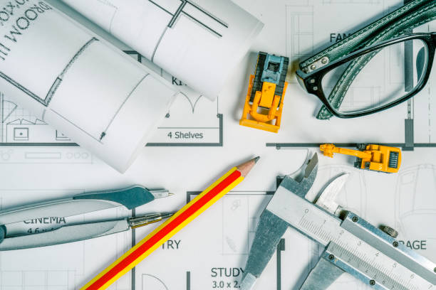 istock Top view of architech drawing on non identified architectural project with various of tools such as divider pencil eye glassed and small heavy equipment machine toys , toned color or instagram tone. 859002786