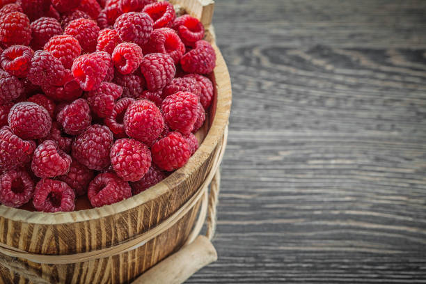 istock Raspberries in bucket on vintage wooden board horizontal image 859006328