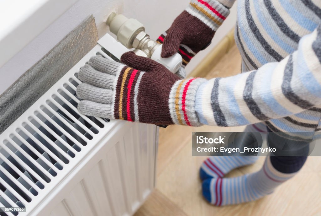 ウール手袋とセーターの子は、ヒータの近くの彼の手を暖めます。 - 冷たいのロイヤリティフリーストックフォト