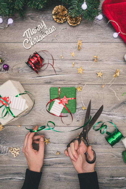 istock Packaging christmas present boxes . Top view of hands on white wood table with fir tree branches, decoration 859024556