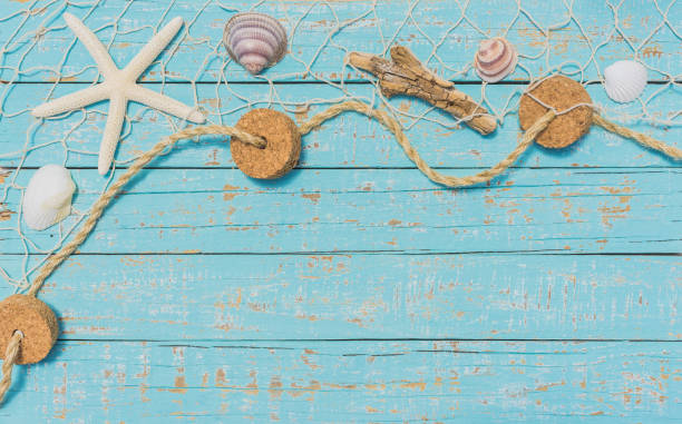 Starfish and Seashell in fishing net on light blue plank background