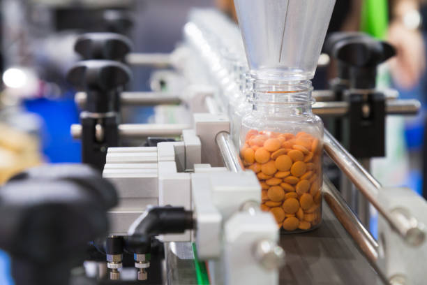 farmaceutische industrie, geneeskunde pillen zijn invullen van de plastic fles op de productielijn machine transportband in de medische fabriek. selectieve aandacht. - farmaceutische fabriek stockfoto's en -beelden