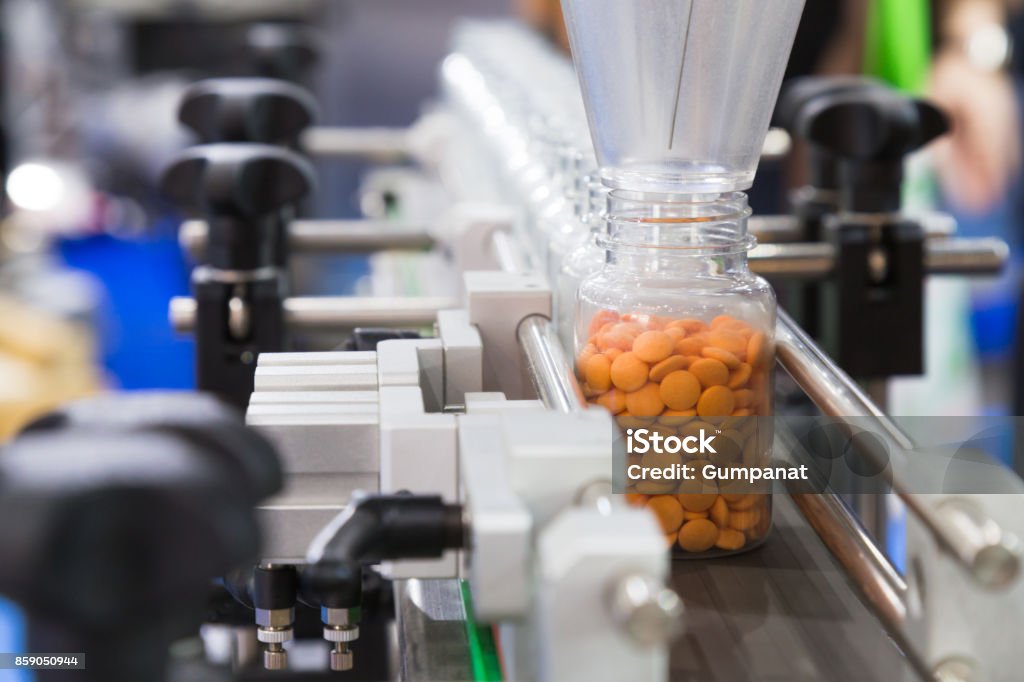 pharmaceutical industry, medicine pills are filling in the plastic bottle on production line machine conveyor at the medical factory. selective focus. Medicine Stock Photo