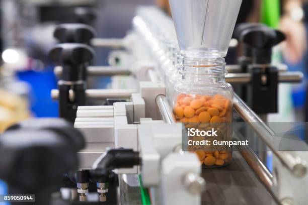 Pharmaceutical Industry Medicine Pills Are Filling In The Plastic Bottle On Production Line Machine Conveyor At The Medical Factory Selective Focus Stock Photo - Download Image Now