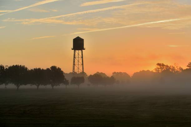 Just another sunrise on the maryland eastern shore near ocean city with the morning mist settled on an orchard and pasture and a nice water tower silhouetted against the sky