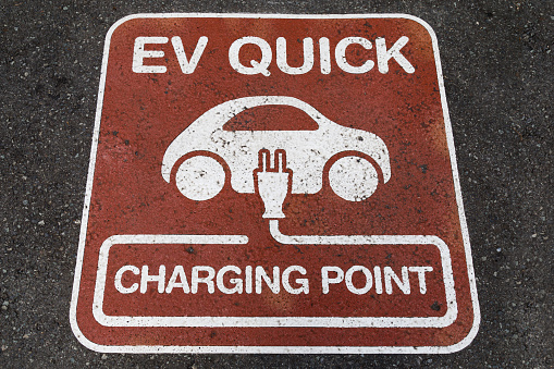 Electric vehicle (EV) quick charging point sign on the asphalt at the charging station point