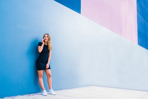 Happy young woman on the mobile phone by a colorful wall