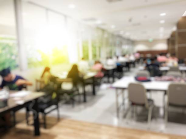 Blurred image of student reading a book, practice homework, preparing for the examination in modern library. Interior modern library for relax education in university.  Education Concept