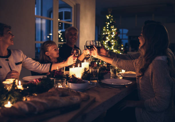 Happy family celebrating christmas together at home Family toasting with wine in a christmas dinner at home in the living room. Happy family celebrating christmas together at home. candle light dinner stock pictures, royalty-free photos & images