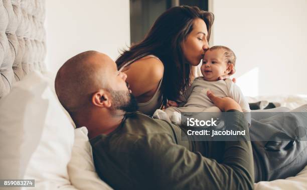 Parents With Their Newborn Baby Boy On Bed Stock Photo - Download Image Now - Baby - Human Age, Newborn, Family