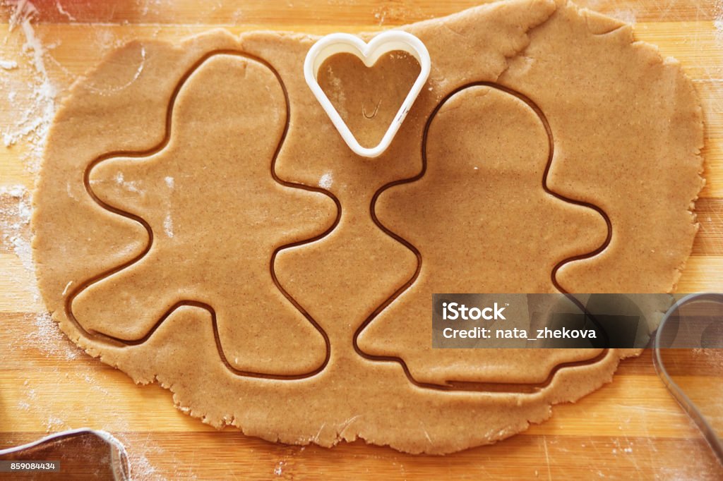 Gingerbread in the shape of a stylized human and other shapes. Cooking and decorating christmas gingerbread. Homemade gingerbread cookies, forms and baking ingredients. Gingerbread man and his wife. Gingerbread in the shape of a stylized human and other shapes. Backgrounds Stock Photo