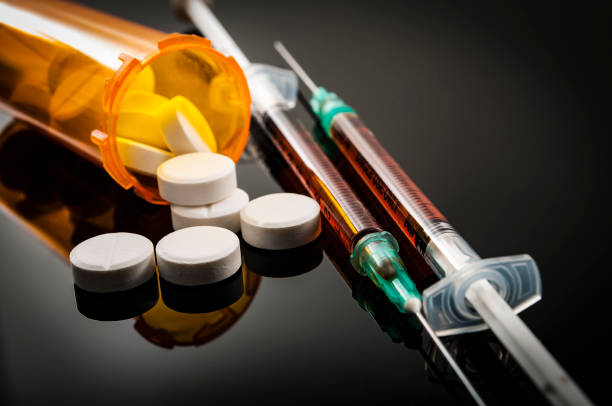 Opioid epidemic, drug abuse concept Opioid epidemic, drug abuse concept with closeup on two heroin syringes or other narcotics surrounded by scattered prescription opioids. Oxycodone is the generic name for a range of opioid painkillers drug overdose stock pictures, royalty-free photos & images