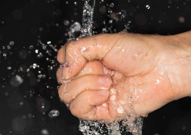 istock hand in water on a black background 859112138
