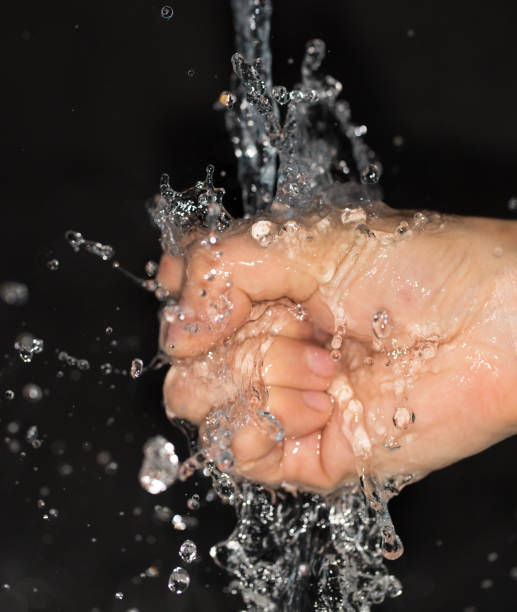 istock hand in water on a black background 859112174