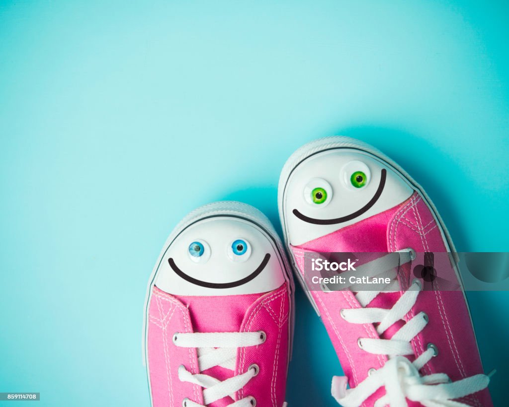 Pink canvas shoes with happy faces on blue background Shoe Stock Photo