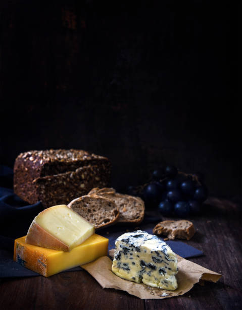 istock cheese, bread and grapes on a rustic wooden table, dark background with generous copy space, vertical, selected focus 859117494
