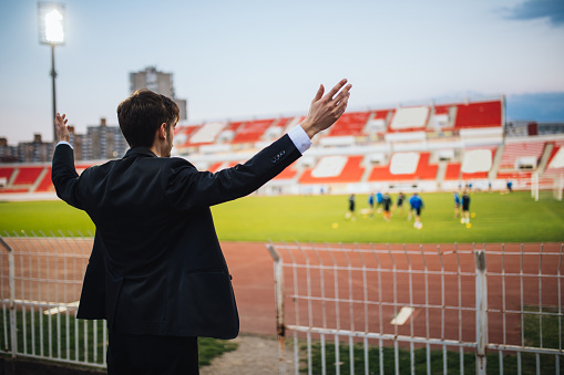 Manager man standing on stadium grandstand with arms outstretched