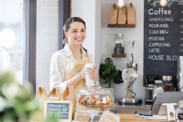 istock Beautiful coffee shop employee greet customer from behind counter 859123414