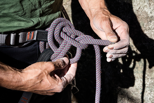 mountain climber tying rope in double bowline knot