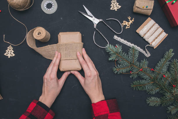 istock Packaging christmas present boxes . Top view of hands on black beckgroun with fir tree branches, decoration 859138788