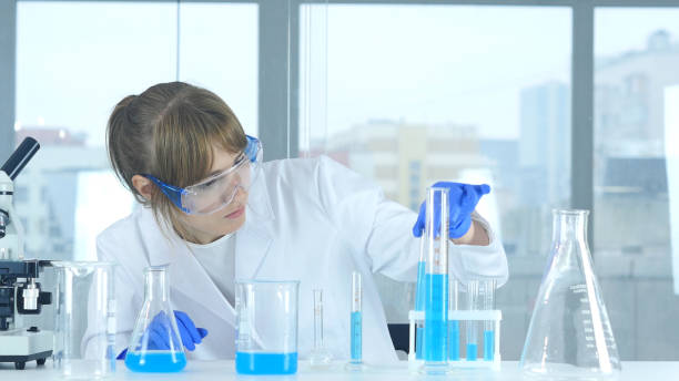 istock Female Scientist Looking at Test Tube blue Solution in Laboratory 859139982