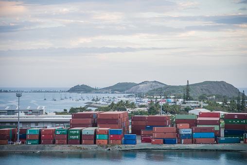 Noumea, New Caledonia: November 25, 2016: Shipyard with stacked cargo containers and view over sailboats in Pacific Ocean harbour in Noumea, New Caledonia