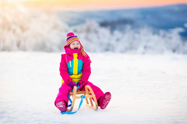 child playing in snow on sleigh in winter park - 13584 imagens e fotografias de stock