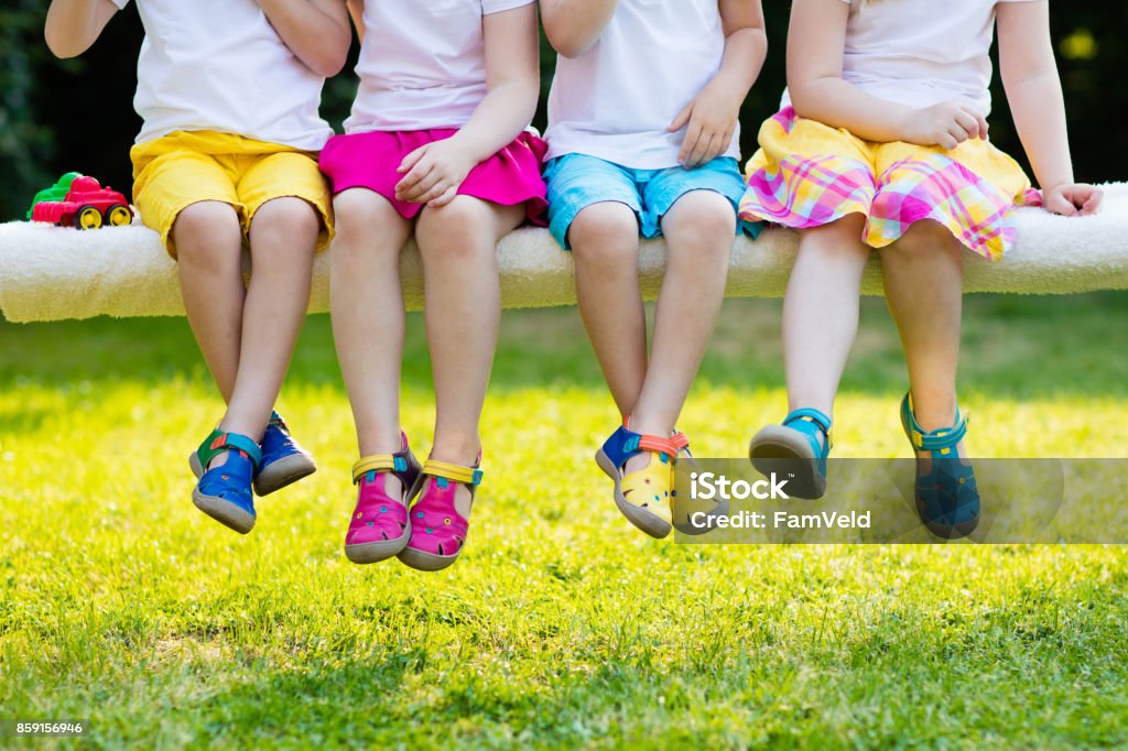 Kids with colorful shoes. Children footwear Footwear for children. Group of preschool kids wearing colorful leather shoes. Sandal summer shoe for young child and baby. Preschooler playing outdoor. Child clothing, foot wear and fashion. Child Stock Photo