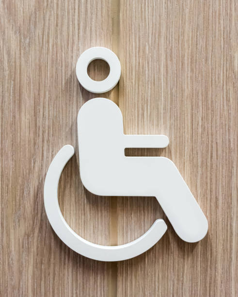 Disable person sign for restroom in white against wooden background. stock photo