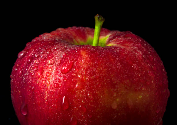 istock Water droplet on glossy surface of red apple on black background 859171308