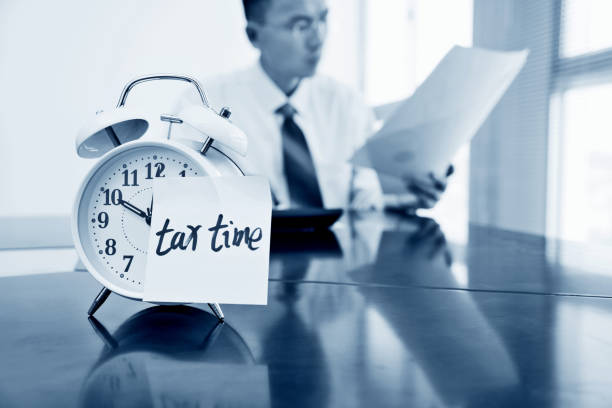Woman hands preparation on individual Income Tax Return on computer laptop wireless devices with reminder Tax Time on 1040 U.S. Individual Income Tax Return Form