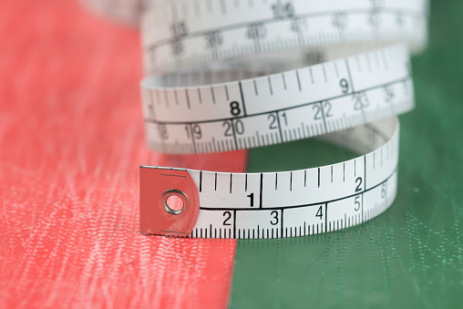 Close up tailor measuring tape on used cabon paper background. White measuring tape shallow dept of field.