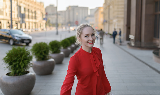 Outdoors portrait of beautiful young woman in a red blouse. Selective focus.