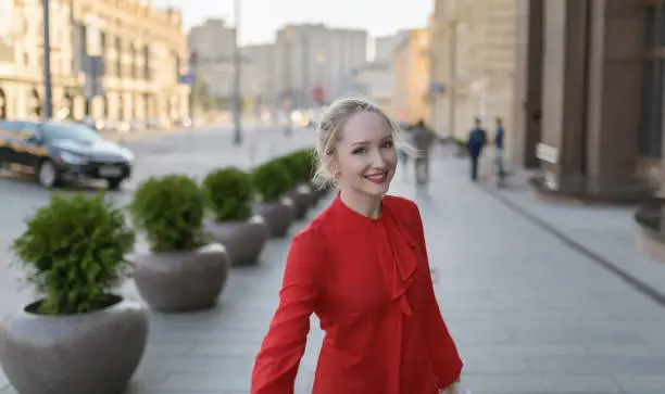 Outdoors portrait of beautiful young woman in a red blouse. Selective focus.