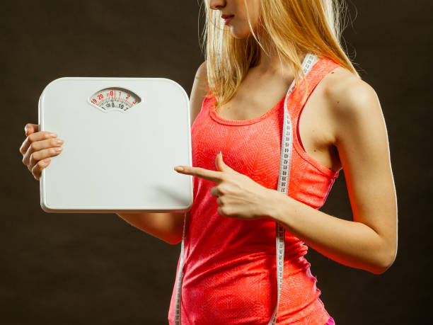 istock gym woman holding weight scale 859232804