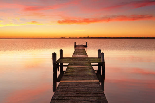 istock Vivid red sunrise over calm waters with timber jetty 859237160