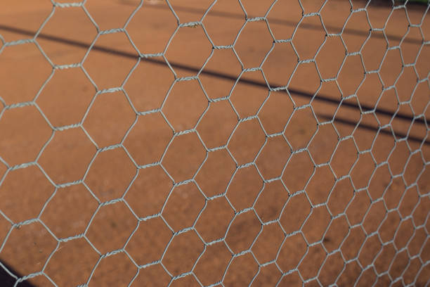 istock Chicken wire fence makes a pattern against an orange or brown ground 859250764