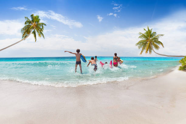 istock Group of kinds running into the sea on sand beach 859253820