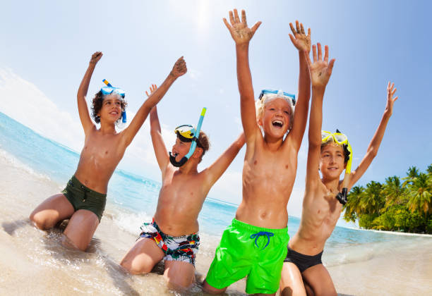 istock Boys sit on the beach in scuba masks lift hands 859253976